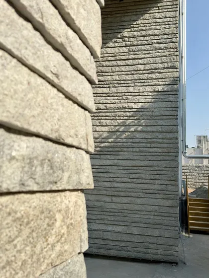 A close-up of the hand-chiseled stone cladding on a recent project. We believe in letting materials speak for themselves, and the texture of this stone, with the marks of the craftspeople who shaped it, tells a story of geological time and human endeavor.