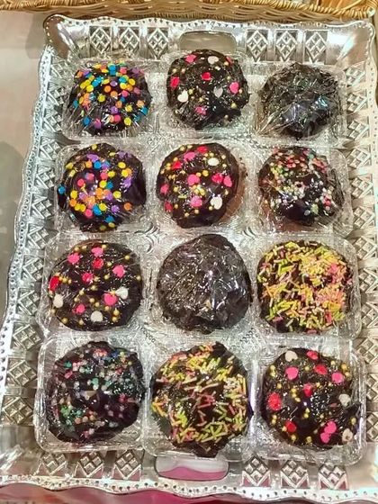 A tray of my rich chocolate cupcakes, individually wrapped for an event. Each one is covered in chocolate and decorated with fun, colorful sprinkles, making them a hit with kids and adults.