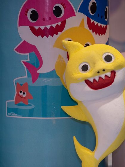 A close-up of the Baby Shark character prop. The bright yellow and cheerful smile perfectly capture the fun and energy of the beloved children's song.