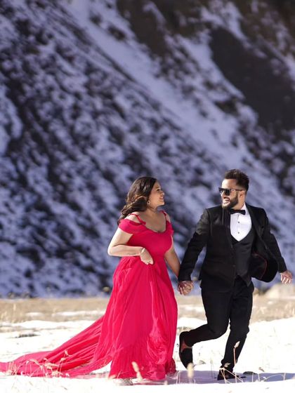 A beautiful shot from a pre-wedding shoot in the snow. The vibrant red of the trail gown stands out beautifully against the white landscape, creating a truly memorable photo.