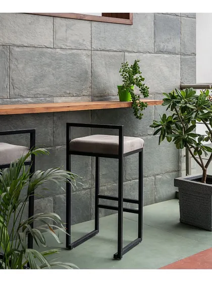 A closer look at the outdoor bar area. The combination of terracotta and green floor tiles with the grey stone wall creates a dark, dreamy backdrop that makes the lush green plants stand out beautifully.