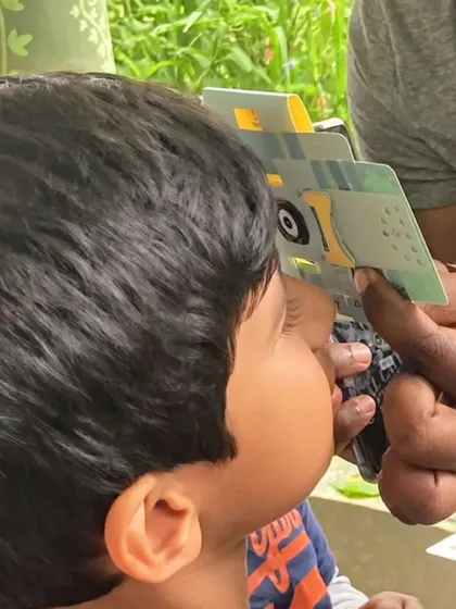 A child using a Foldscope, a portable paper microscope, to get a closer look at nature. It's a fantastic tool for budding scientists.