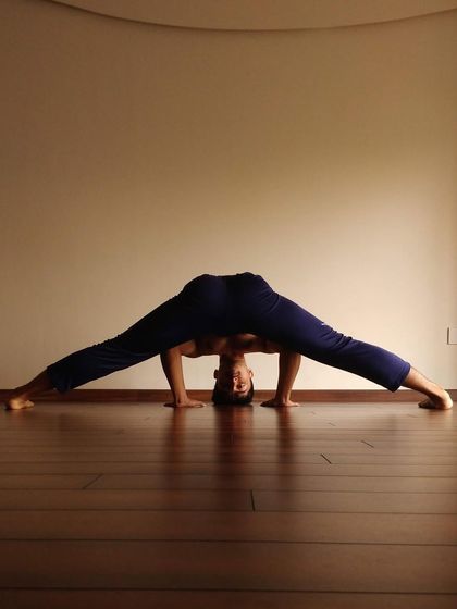 A demonstration of a deep wide-legged forward fold, highlighting the importance of stretching the adductors and hamstrings for hip mobility and pelvic alignment.