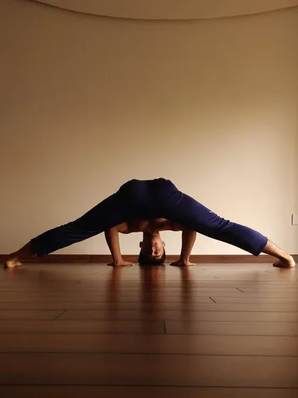 A demonstration of a deep wide-legged forward fold, highlighting the importance of stretching the adductors and hamstrings for hip mobility and pelvic alignment.
