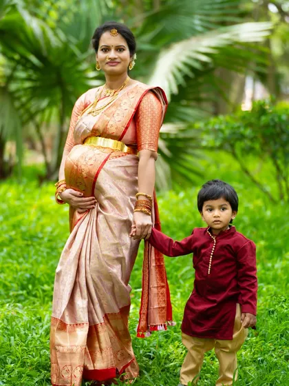 The sweet anticipation of a new arrival is a precious family moment. We specialize in maternity shoots that include older siblings, capturing the unique bond and excitement as your family grows. This outdoor portrait in a beautiful silk saree shows a quiet, loving moment between a mother and her son.