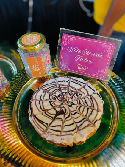 A "White Chocolate Fantasy" waffle, artfully drizzled with chocolate, ready to be served.