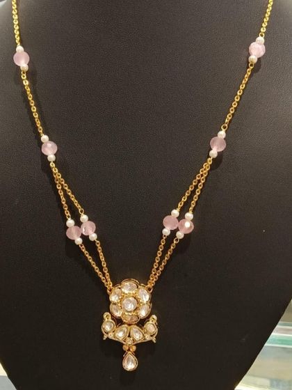 A delicate double-strand necklace with a floral Kundan pendant and soft pink beads. This is a perfect piece for a thoughtful gift or for adding a touch of elegance to your everyday style.