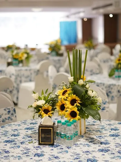A close-up of a guest table centerpiece, featuring vibrant sunflowers that add a pop of color to the blue and white floral theme. It's these details that tie the whole event together.