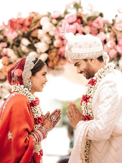 A moment of mutual respect and love during the wedding ceremony. The couple greets each other with a traditional 'namaste', their smiles reflecting the happiness of their union.