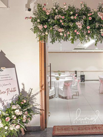 A welcoming entrance to a baptism reception, with a beautiful floral arrangement and a personalized sign.