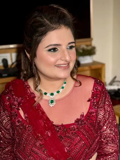 A smiling shot that shows how the makeup complements the beautiful emerald jewelry. The look is balanced, elegant, and party-ready.