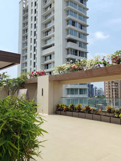 This image showcases the combination of lush bamboo in a large planter and a row of colorful crotons, providing both privacy and aesthetic appeal to this spacious terrace.