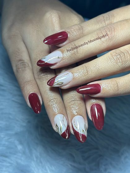 A beautiful bridal set with a deep red base, nude accent nails, and delicate gold leaf details.