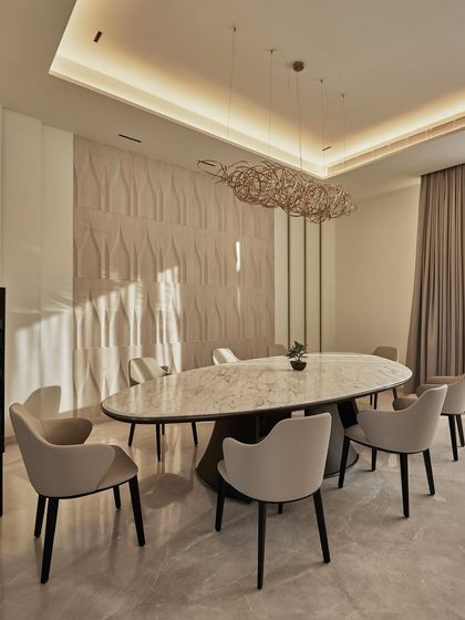 In the Ananda project, the dining room is a space crafted for quiet conversations. A textured feature wall catches the light beautifully, creating an interplay of curve and shadow. The oval marble table and sculptural light fixture complete the serene composition.