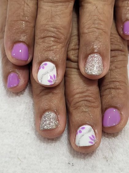 A cute and simple design on natural nails. This set combines a soft lilac color with silver glitter accent nails and delicate, hand-painted floral details.