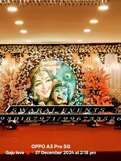 An elaborate Krishna-themed stage for a baby shower or 'dohale jevan'. This grand setup includes a large backdrop, a floral moon prop, and character cutouts, perfect for a large celebration.