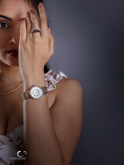 A partial reveal, creating intrigue and focusing on the details. The watch and ring become part of the story, hinting at a character who values time and elegance.