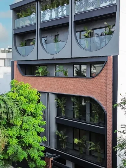 Another angle of the Patel Nagar facade, highlighting the interplay of curved forms and the texture of the brickwork. The integrated planters add a touch of green to the modern urban design.