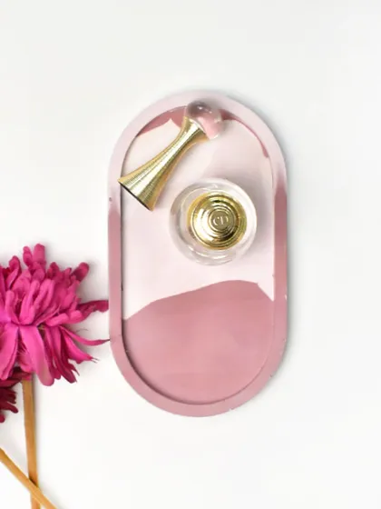 A still shot of our pink marbled oval trinket tray, perfect for holding your favorite perfume.