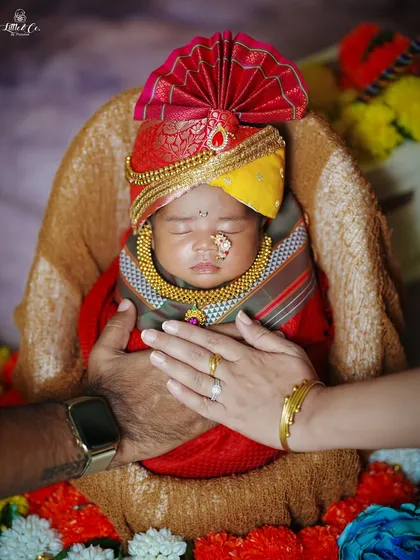 A newborn baby, dressed in a traditional turban and wrap, is gently held by his parents' hands, symbolizing love and blessings on Gudi Padwa.