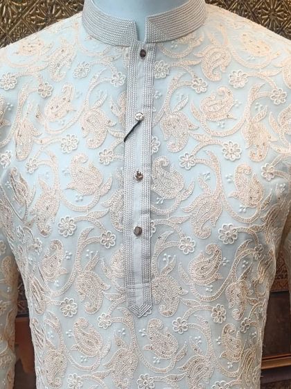 A classic off-white kurta with delicate peach-colored paisley and floral threadwork. This is a timeless and elegant option for any daytime ceremony.