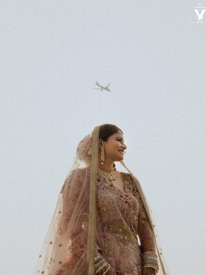 A unique bridal portrait with an airplane flying in the sky above her. This serendipitous moment adds a touch of modern storytelling to a classic, beautiful shot.