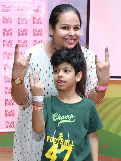 A mother and son show off their inked fingers and make fun gestures after participating in an activity.