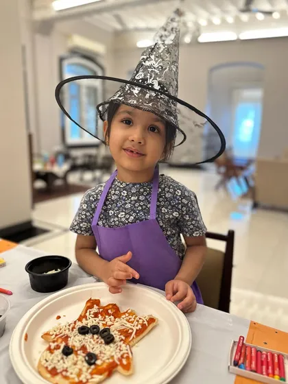 A sweet smile from a young baker and her spooky, hand-shaped pizza. She did a fantastic job creating her own Halloween masterpiece.