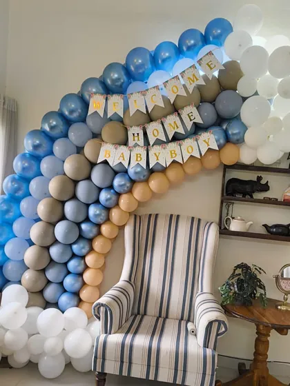 A beautiful balloon cloud in shades of blue, beige, and white, created as a backdrop for a baby arrival celebration at home.