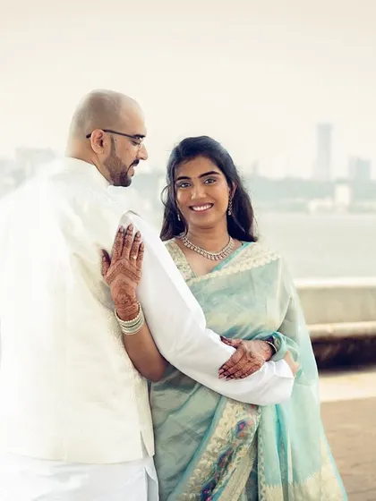 A candid pre-wedding shot with the Mumbai skyline in the background, capturing a natural moment of connection between the couple.