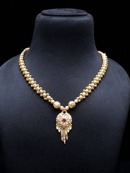 A delicate gold-beaded necklace with a small, intricate pendant. This is a perfect piece for those who prefer minimalist yet traditional jewellery.