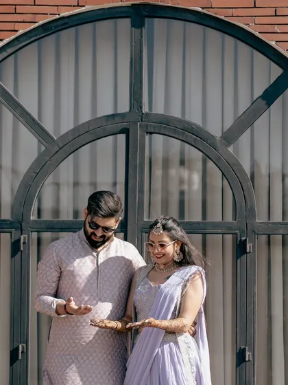 The couple showing off their mehndi-adorned hands, a playful and happy moment captured in beautiful natural light.