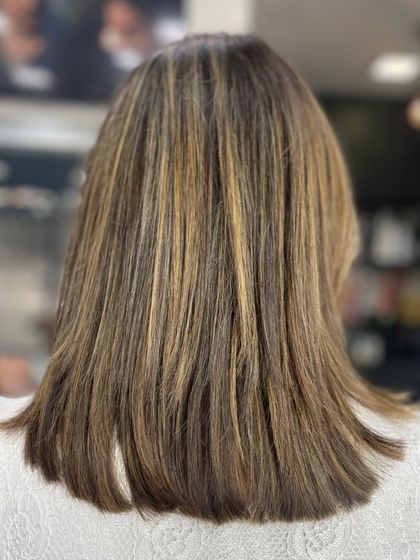 A sleek, straight haircut with golden-blonde highlights, creating a sharp and modern look.