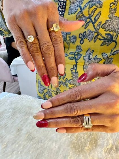 A full view of the red and gold French twist nails. The client is wearing them beautifully with her rings, showing how they can be a great accessory.