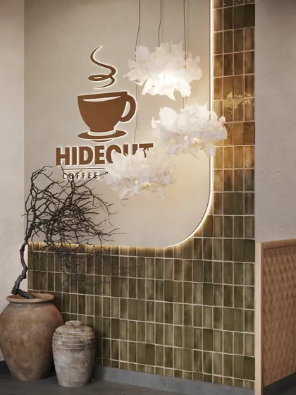 Details make the design. At the entrance of Hideout Cafe, we paired rustic elements like the terracotta pots with sophisticated touches like the glossy green tiles and delicate, cloud-like pendant lights. This combination creates a unique and memorable entry point for customers.