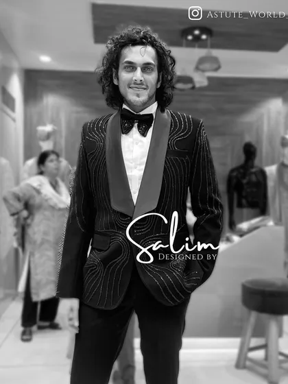 A client in a black tuxedo with sparkling wave-like embroidery. The monochrome black-and-white photo highlights the texture and pattern of the design.