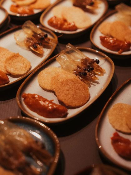 An inventive seafood appetizer. This dish features crispy fried prawn heads for texture, served alongside prawn crackers and a dollop of our house-made sambal for a spicy kick.