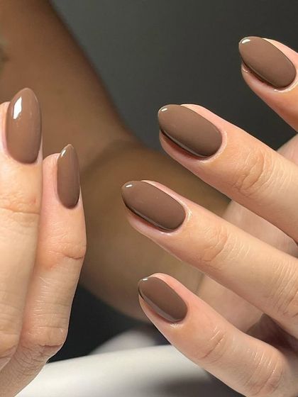 The way the light hits these glossy brown nails shows off the flawless application. It’s a versatile color that can be dressed up or down.