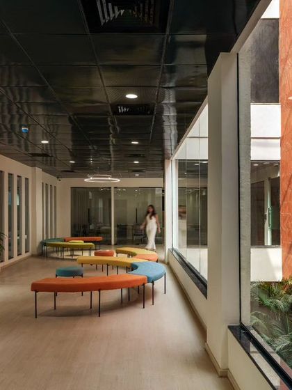 The waiting lounge at Campus Biovet, filled with natural light from the adjacent courtyard. The design is simple with oak flooring and playful, colourful furniture, creating a dynamic and welcoming atmosphere.