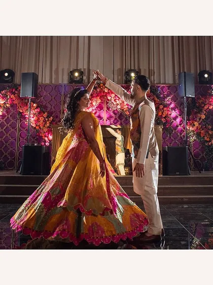 The couple shares a dance at their Sangeet. The twirl of her multi-colored lehenga creates a beautiful cascade of festive hues.