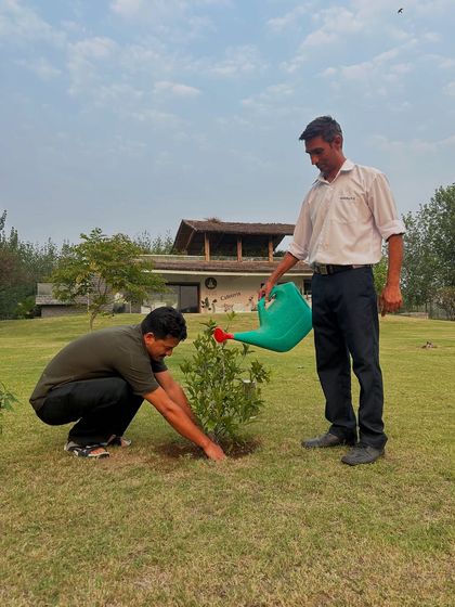 Nurturing the future, one drop at a time. A member of our team waters a newly planted sapling, a beautiful moment of care and connection with nature at our retreat.
