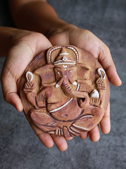A finished relief tile of Lord Ganesha, held in cupped hands, showcasing the beautiful detail and craftsmanship.