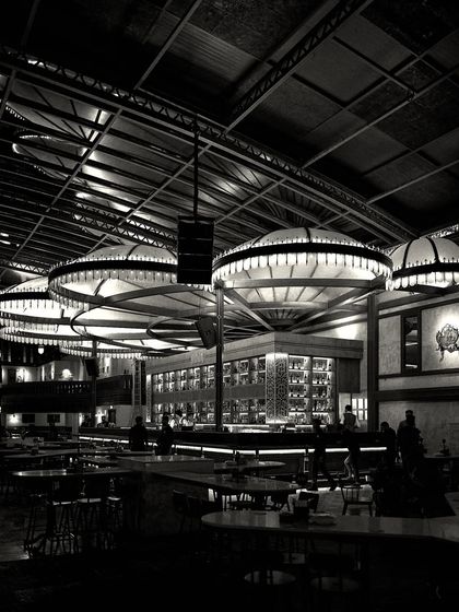 The bar from a distance, captured in dramatic black and white. The lighting creates a strong contrast, highlighting the structure of the ceiling and the central bar.