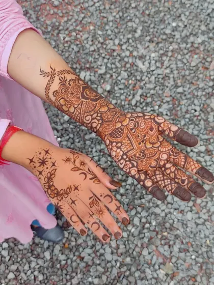 A fun comparison of two different styles. One hand has a full, intricate party design, while the other features a very modern, minimalist celestial pattern.