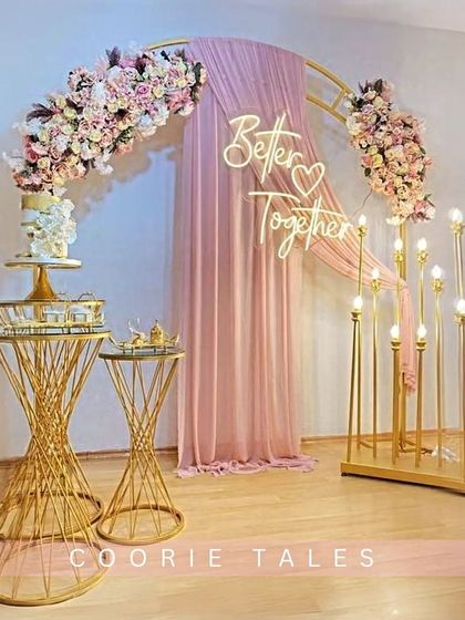 Celebrating that you're "Better Together" with this romantic setup. It features a golden arch, soft pink draping, a custom neon sign, and elegant floral arrangements, creating the perfect photo-ready moment for an engagement or anniversary.