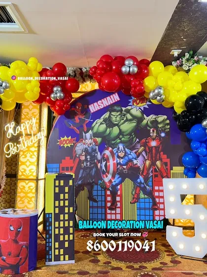 An Avengers theme for a 5th birthday party. This action-packed setup features a superhero backdrop, a city skyline, and a colorful balloon arrangement.