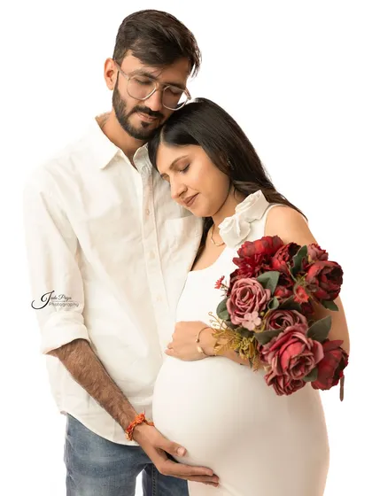 Adding a simple prop like a bouquet of flowers can bring a touch of color and tenderness. This couple shares a gentle embrace in this serene, light-filled portrait.