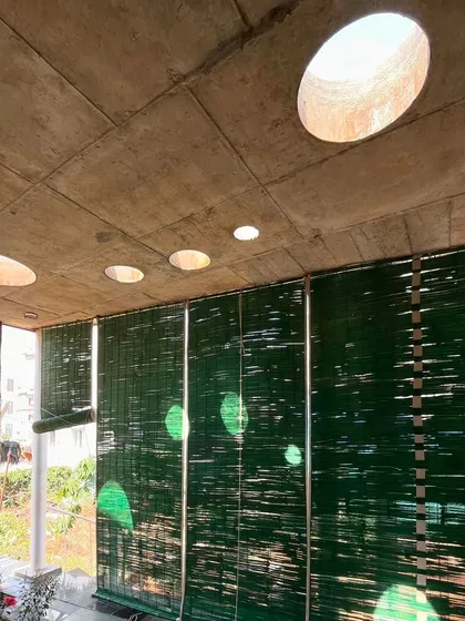 (Duplicate of 46) The interplay of light from the circular skylights and the green bamboo blinds creates a serene and inspiring atmosphere within the artist's studio.