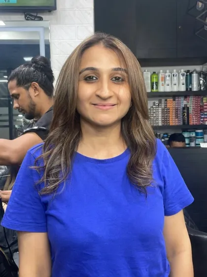 A bright and happy client showing off her new light brown hair color with subtle highlights.