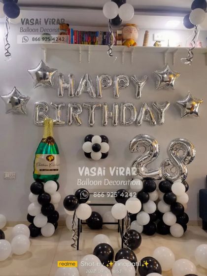 A classic and elegant setup for a 28th birthday. We used black, white, and silver balloons with star accents and a large champagne bottle foil balloon to create a sophisticated party corner.